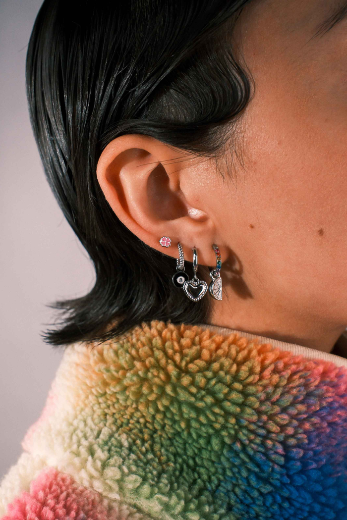 Close-up of an ear with multiple earrings against a blurred background