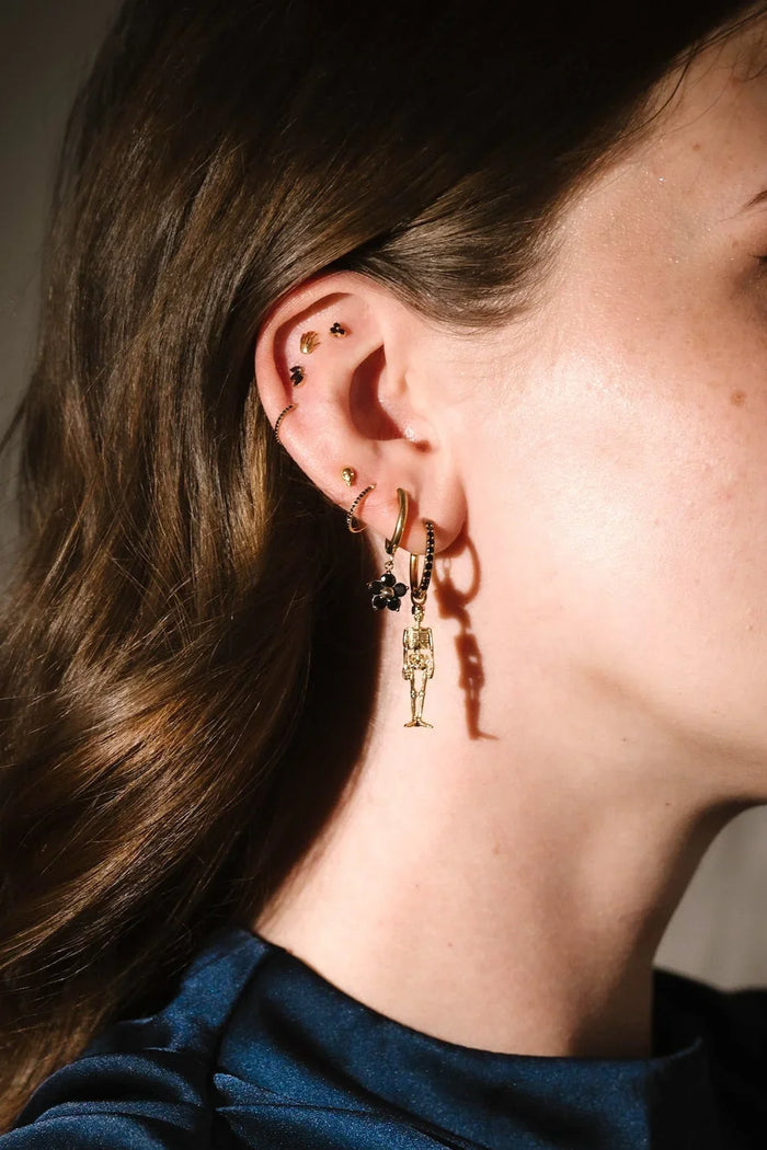 Gold and black earrings worn on an ear