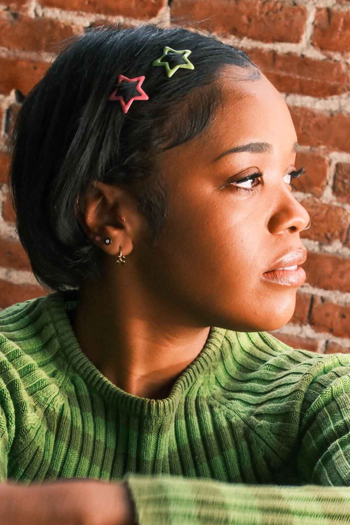 Photo of a model wearing multiple earrings, including a lightning bolt shaped flat back stud in hot pink enamel