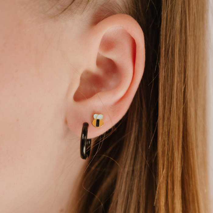 A close up of a bumblebee shaped flat back stud with yellow and black enamel and gold-plated titanium metal.