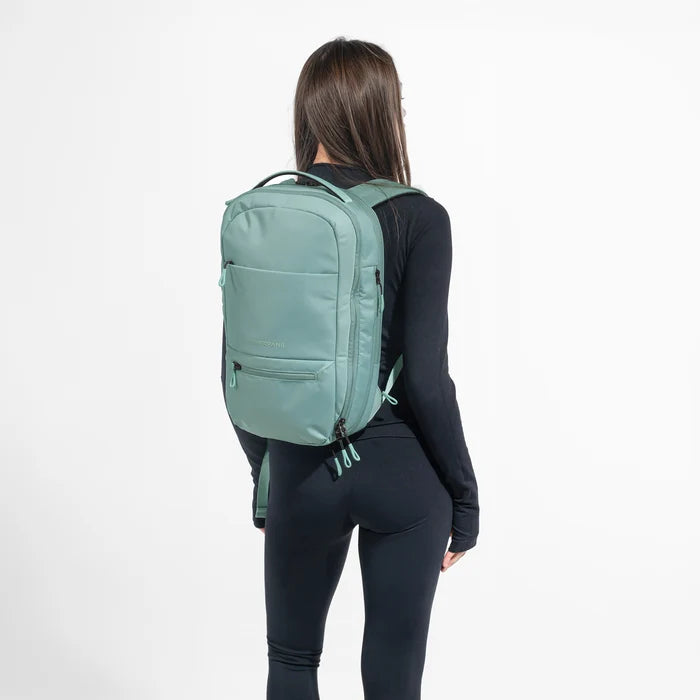 Woman wearing a Sherpani Camden Surf Blue Ultimate Backpack on her back against white background. #color_surf-blue