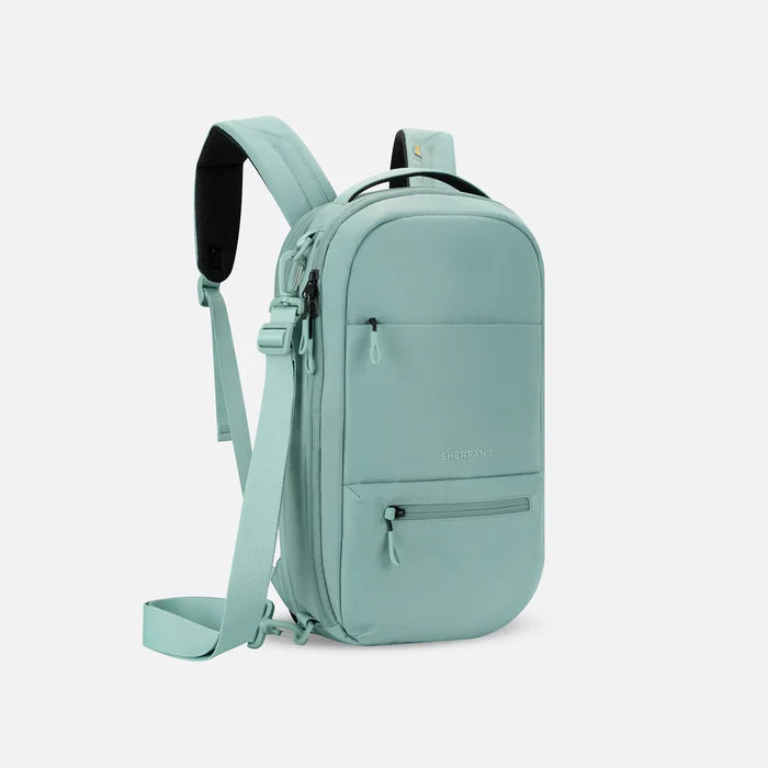 A Sherpani Camden Surf Blue Ultimate Backpack, 3/4 view showing various pockets and strap options on white backdrop. #color_surf-blue