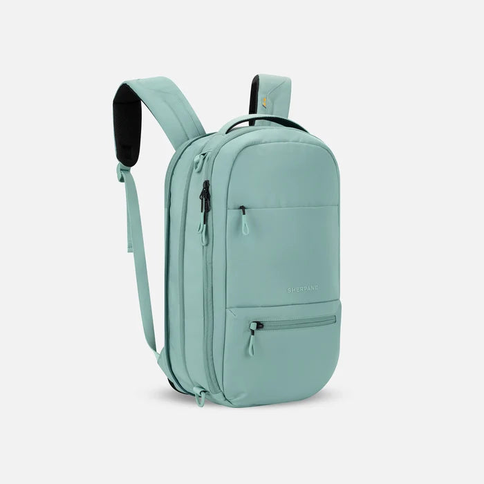 A Sherpani Camden Surf Blue Ultimate Backpack, 3/4 view showing unzipped extender and strap options on white backdrop. #color_surf-blue
