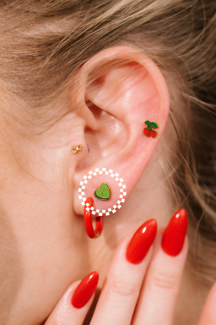 Close-up of an ear with colorful earrings and red nail polish.