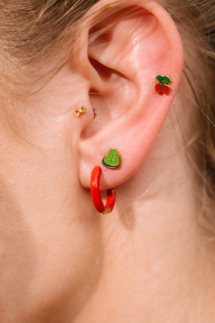 Close-up of an ear with colorful earrings on a neutral background