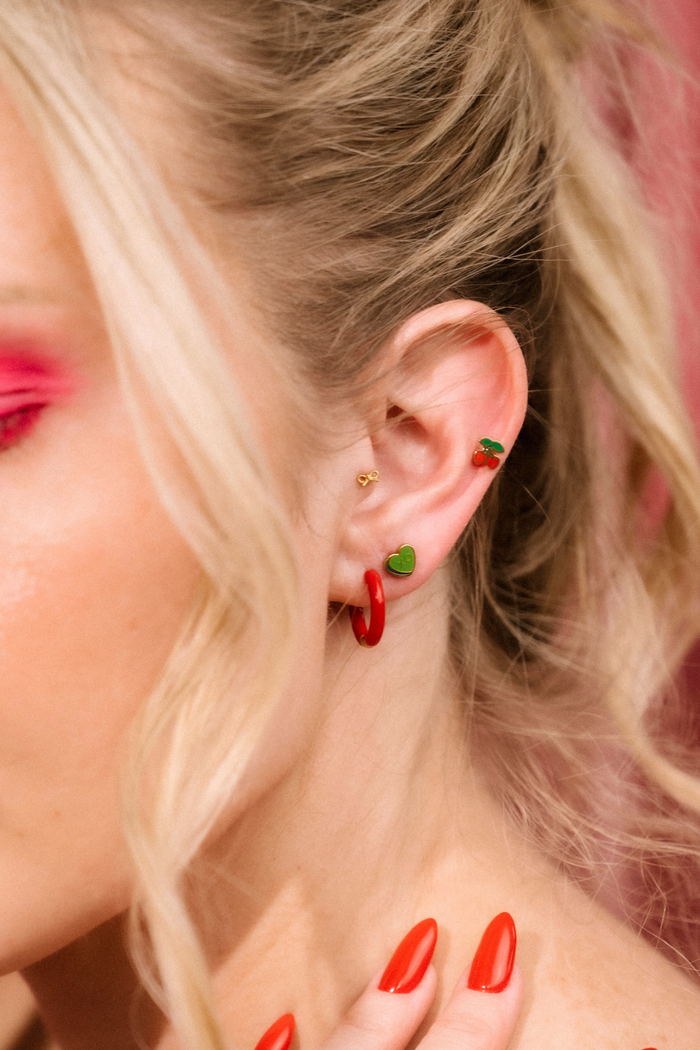 Close-up of a person wearing earrings with green and red accents.