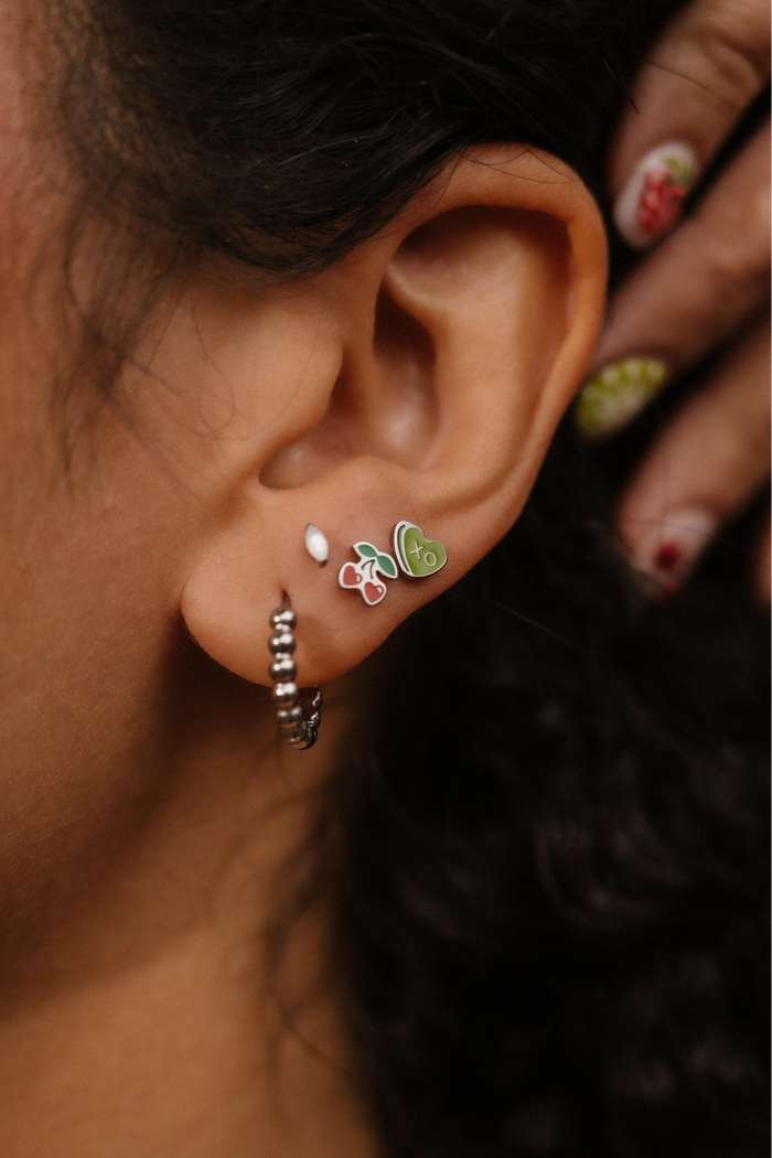 Close-up of an ear with multiple earrings, including a butterfly design.