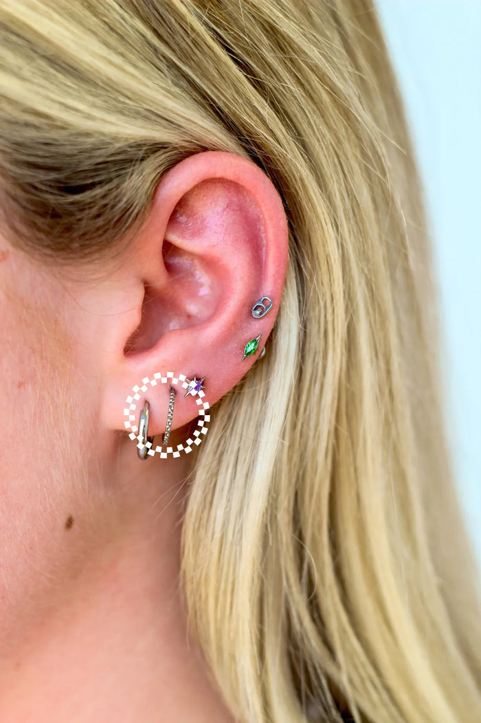 Close-up of an ear with multiple earrings on a plain background