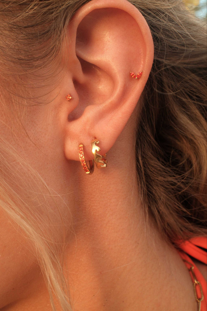 Close-up of an ear wearing gold hoop earrings with a blurred background