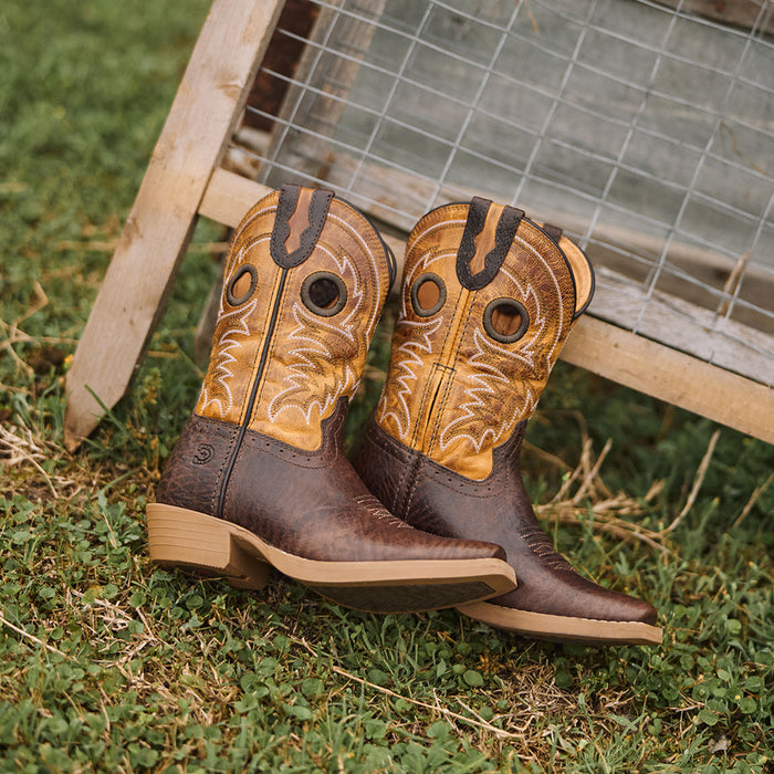 Pair of brown and golden kids' cowboy boots on grass