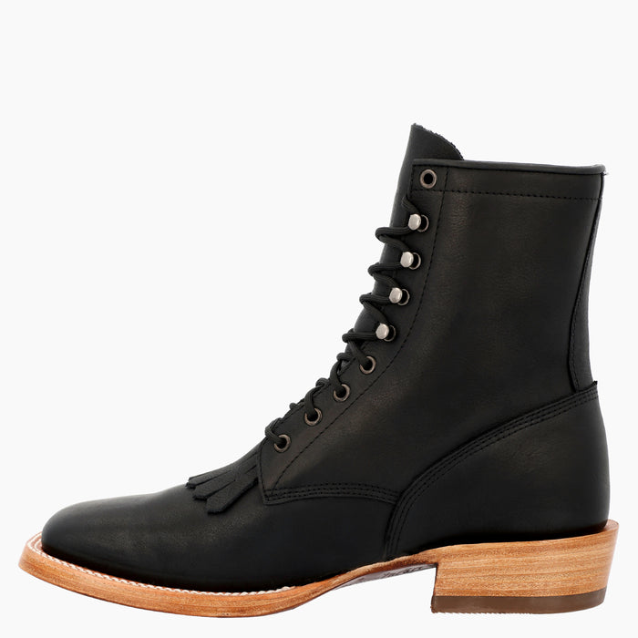 A black leather lace-up ankle boot with a low stacked leather heel, tassel detail on the vamp, and silver metal eyelets, shown from a side profile against a plain white background.