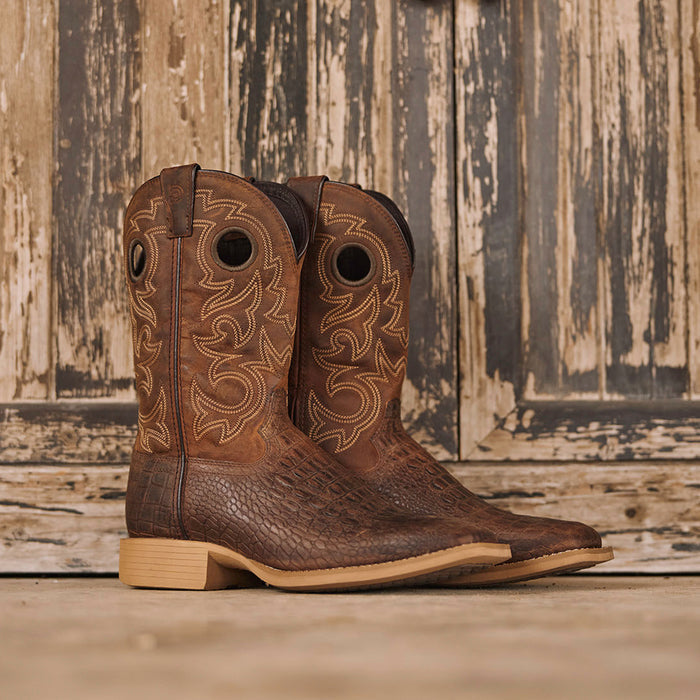 Brown cowboy boots with crocodile print on a rustic wooden background