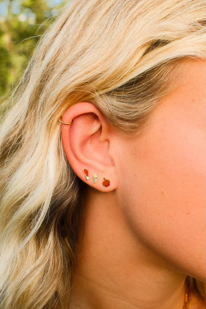 Close-up of a person wearing earrings with a blurred natural background