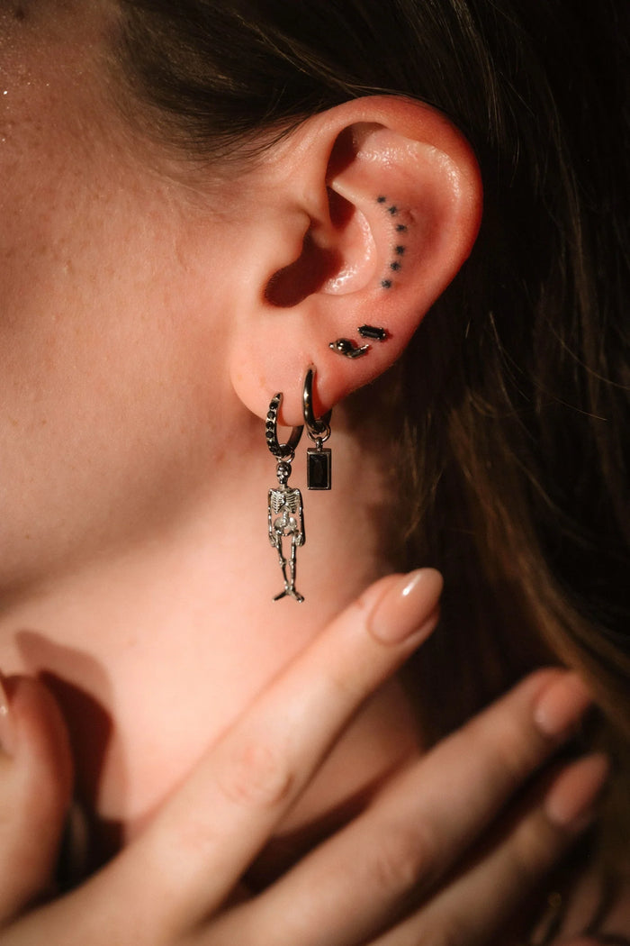 Close up of on ear wearing silver and black earrings