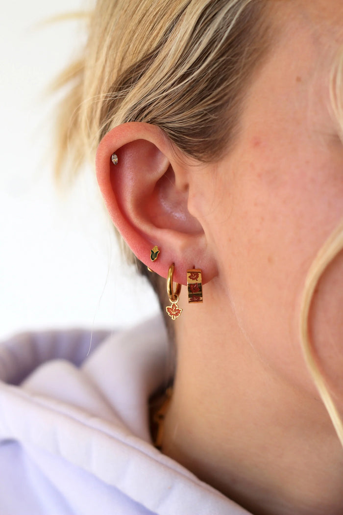 Close-up of a person wearing gold hoop earrings with a blurred background