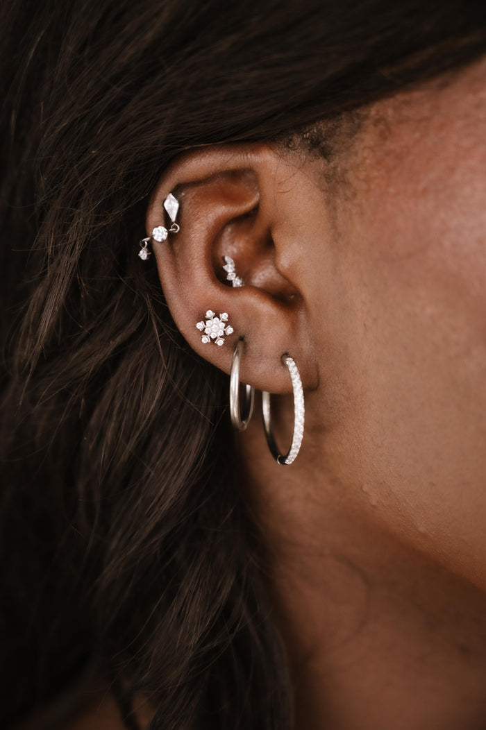 Close-up of an ear with multiple silver and clear zirconia earrings