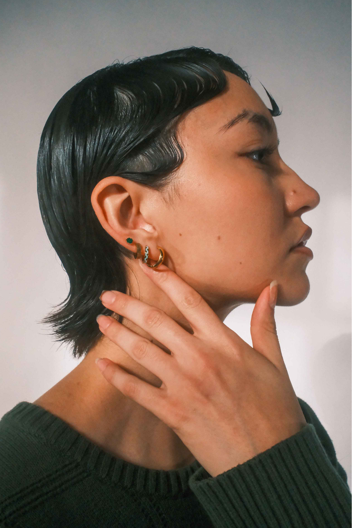 Person wearing gold hoop earrings with a neutral background