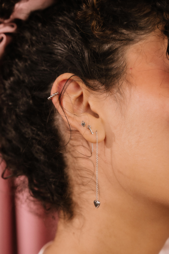 Close-up of an ear with multiple silver earrings against a blurred background