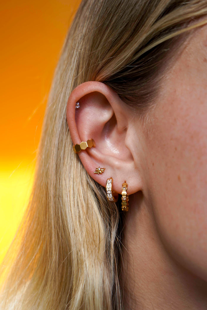 Close up of a model wearing a cuff earring made from stacked hexagon shapes. Hoop made from stainless steel.