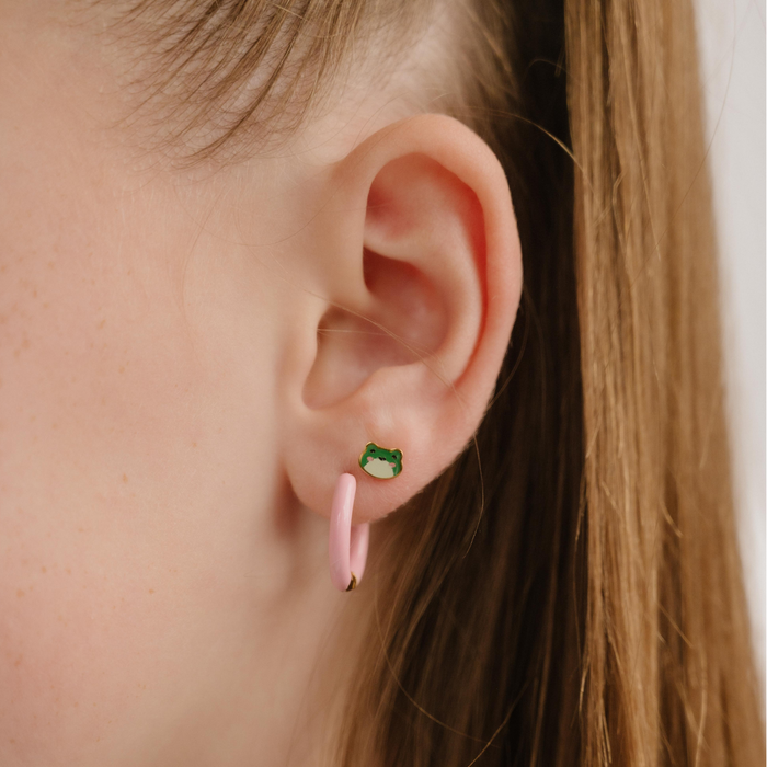 A close up of a frog shaped flat back stud with green enamel and gold-plated titanium metal.