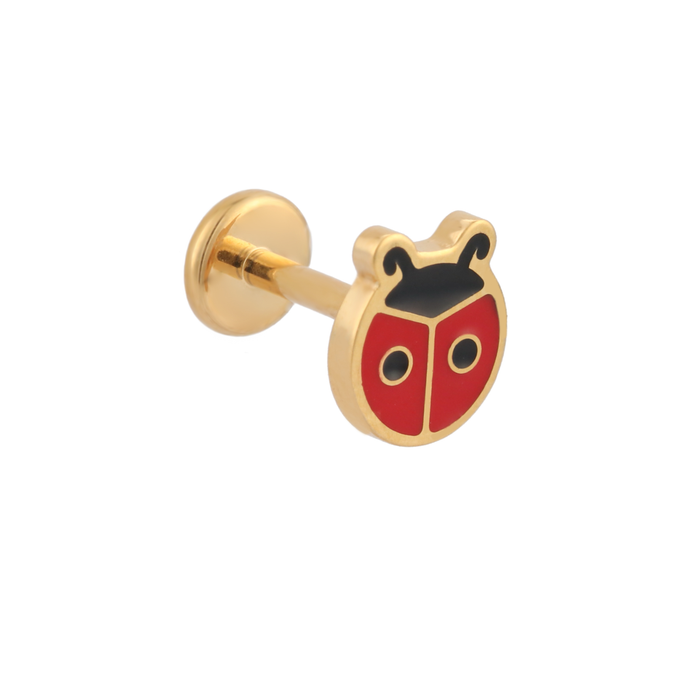 A close up of a ladybug shaped flat back stud with red enamel and gold-plated titanium metal on a white background