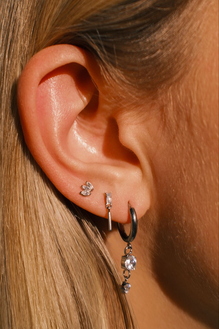 Close-up of an ear with multiple earrings against a blurred background