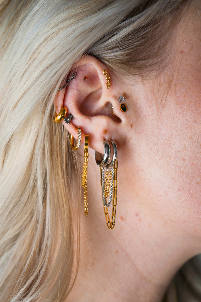 Close-up of an ear with multiple gold hoop earrings and a blurred background