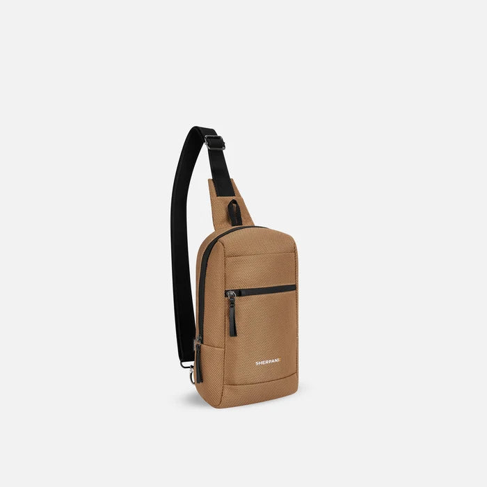 A Sherpani Metro Sand Anti-theft Reversible Sling, 3/4 view showing strap & lockable pocket on white background.  #color_sand-tan