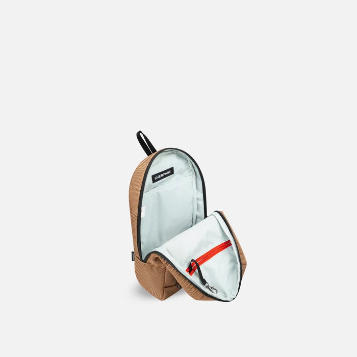 A Sherpani Metro Sand Anti-theft Reversible Sling, 3/4 view open showing inside pocket against white background. #color_sand-tan