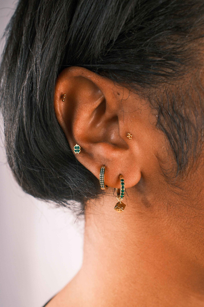 Close-up of an ear with multiple earrings on a neutral background