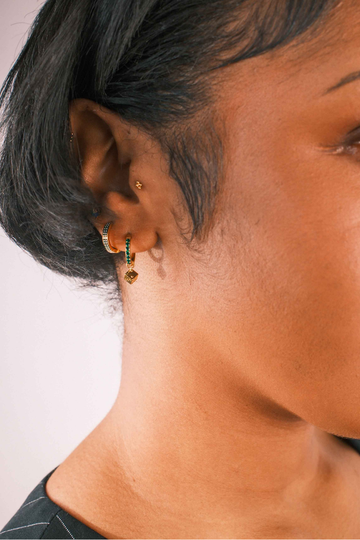 Close-up of an ear with multiple earrings on a neutral background