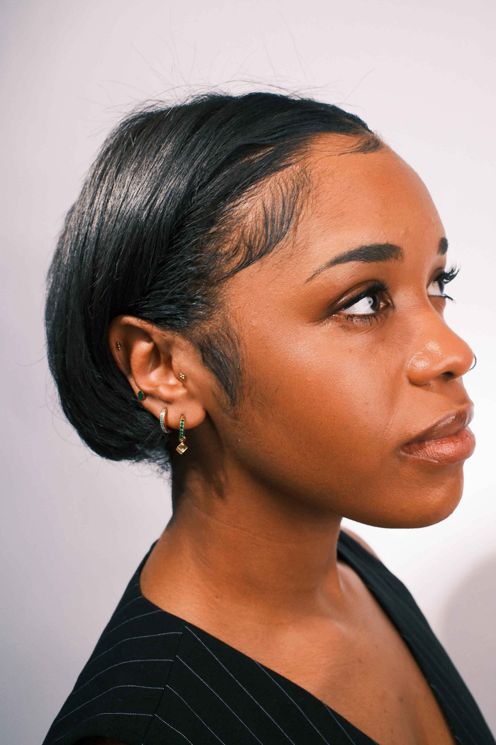 Close-up of an ear with multiple earrings on a neutral background