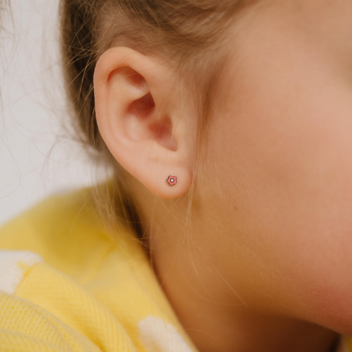A close up of a daisy shaped flat back stud with pink enamel and gold-plated titanium metal.