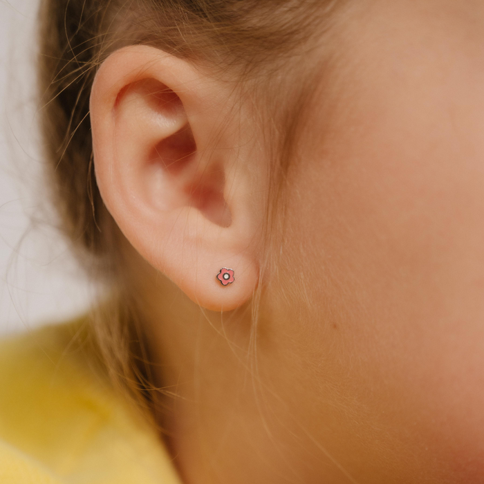 A close up of a daisy shaped flat back stud with pink enamel and gold-plated titanium metal.