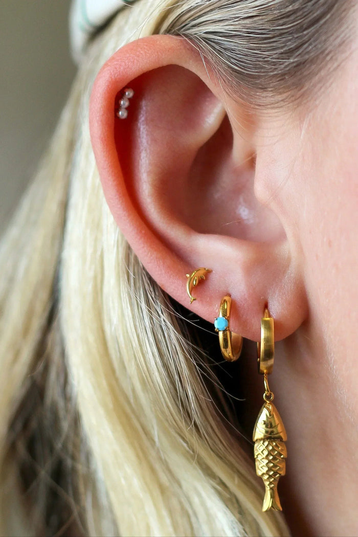 Close-up of an ear with gold earrings and a blurred background