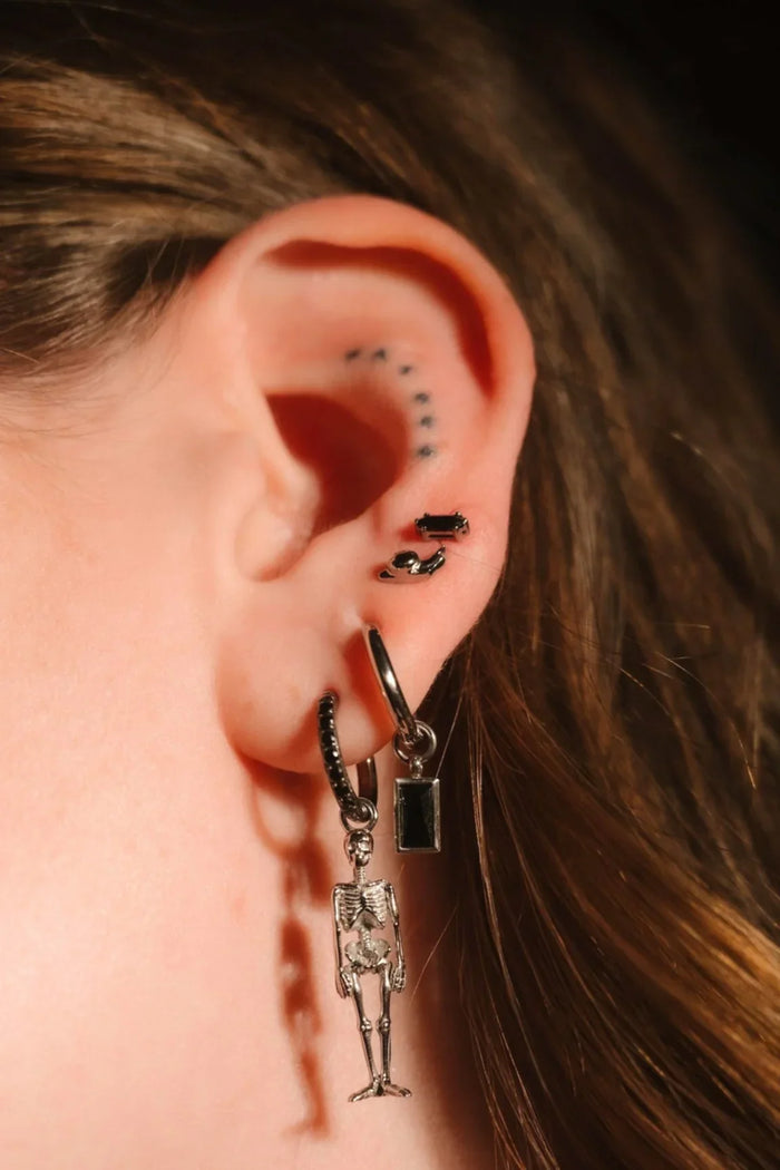 Black and silver earrings worn on an ear