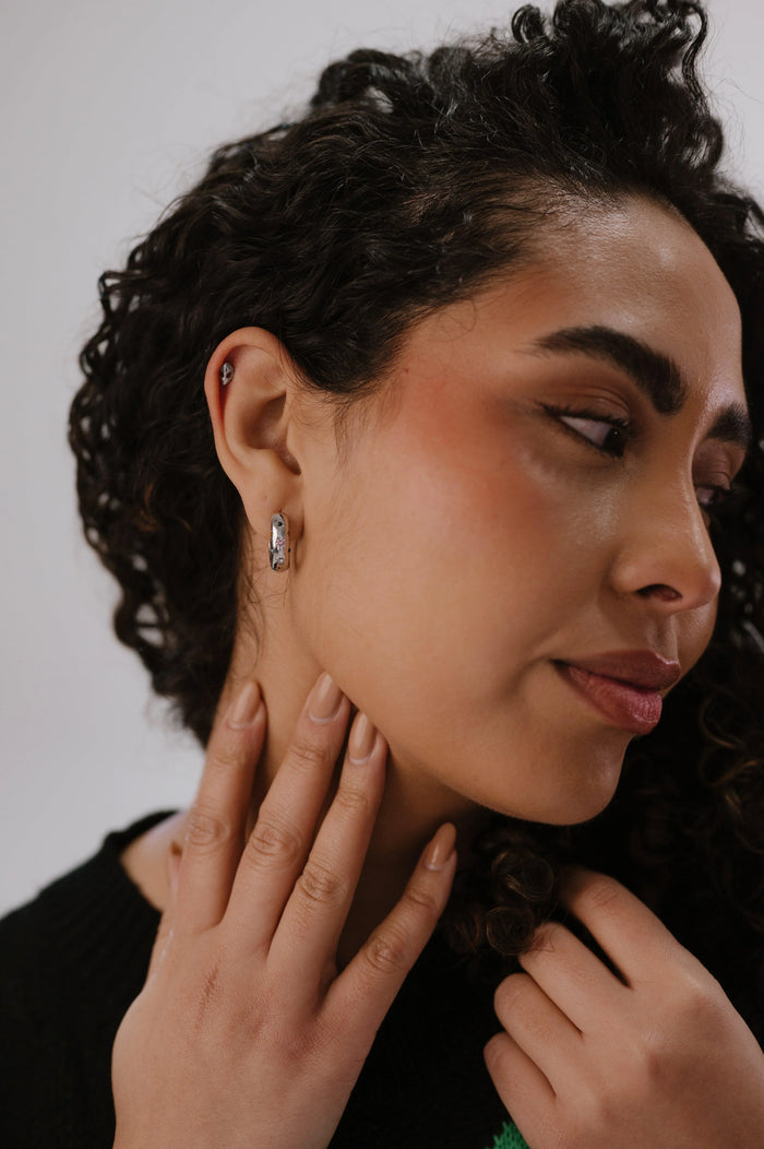 Woman wearing a diamond earring with a neutral background