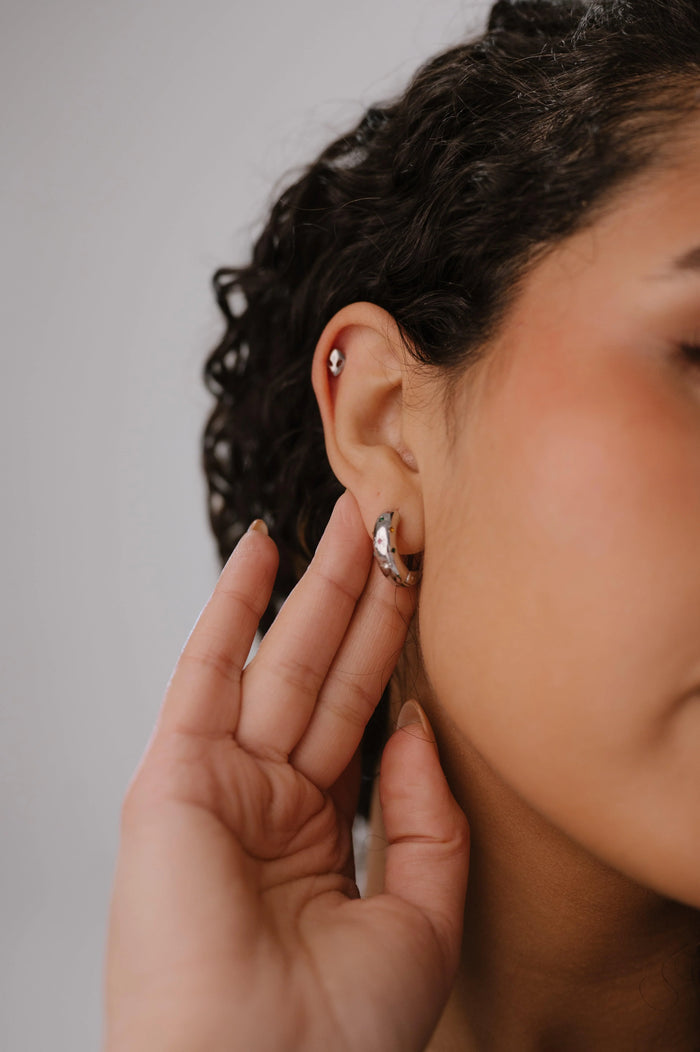 Close-up of a person wearing earrings with a neutral background