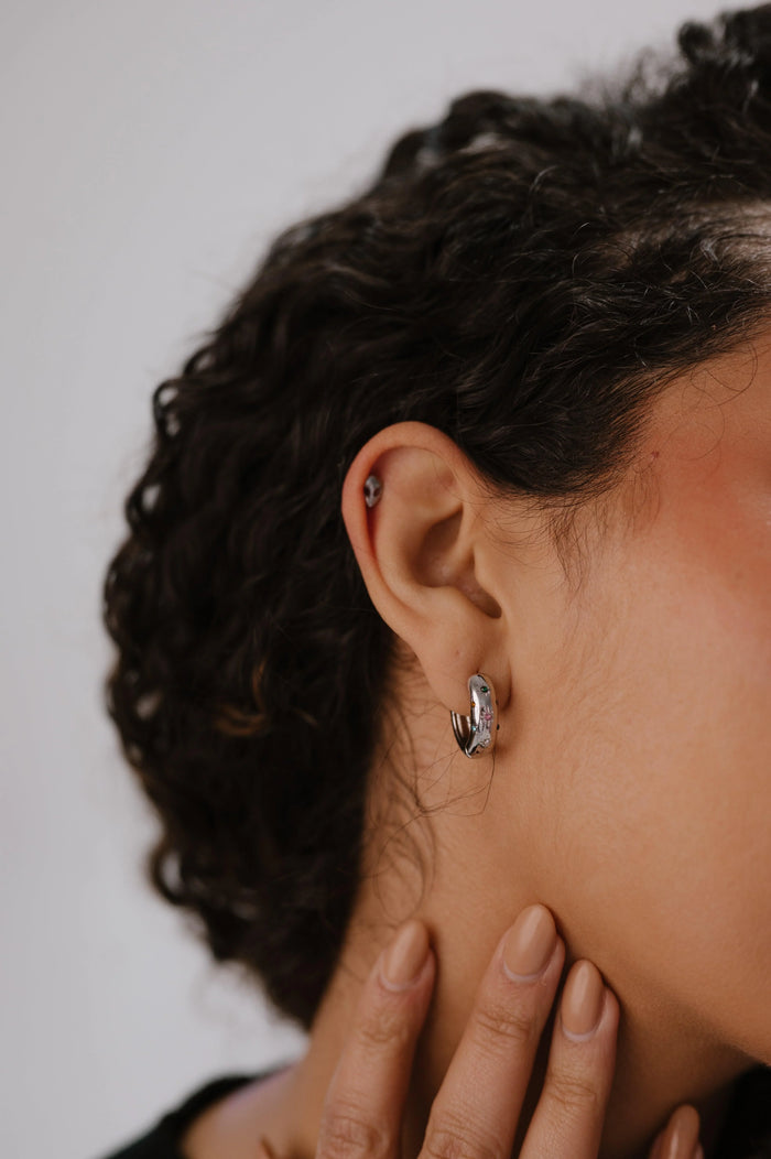 Close-up of an ear with a hoop earring against a neutral background