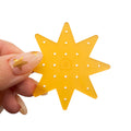 Yellow star or sun-shaped acrylic piece with holes held by a hand on a white background
