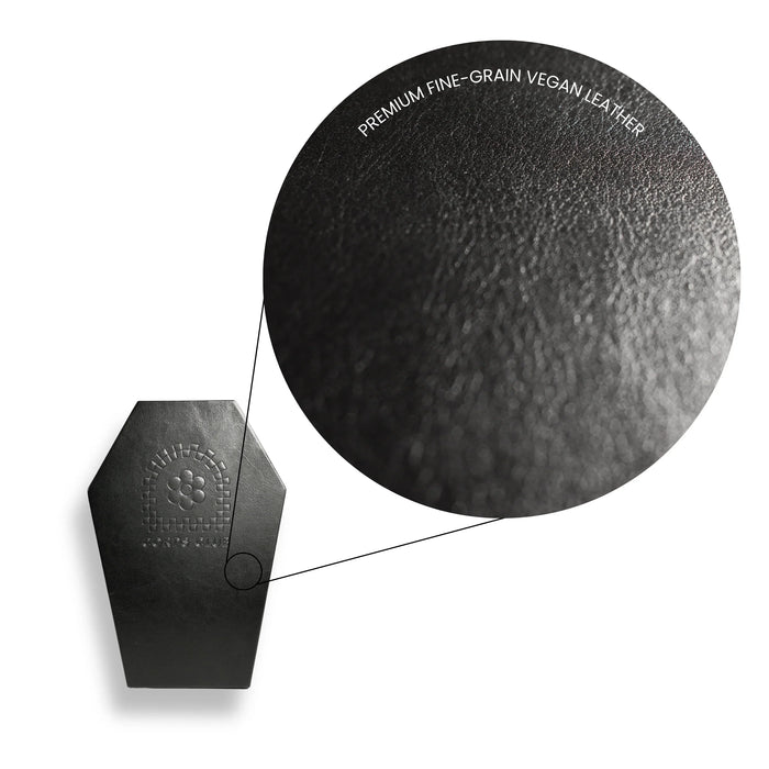 Close-up of a black vegan leather product with texture details on a white background