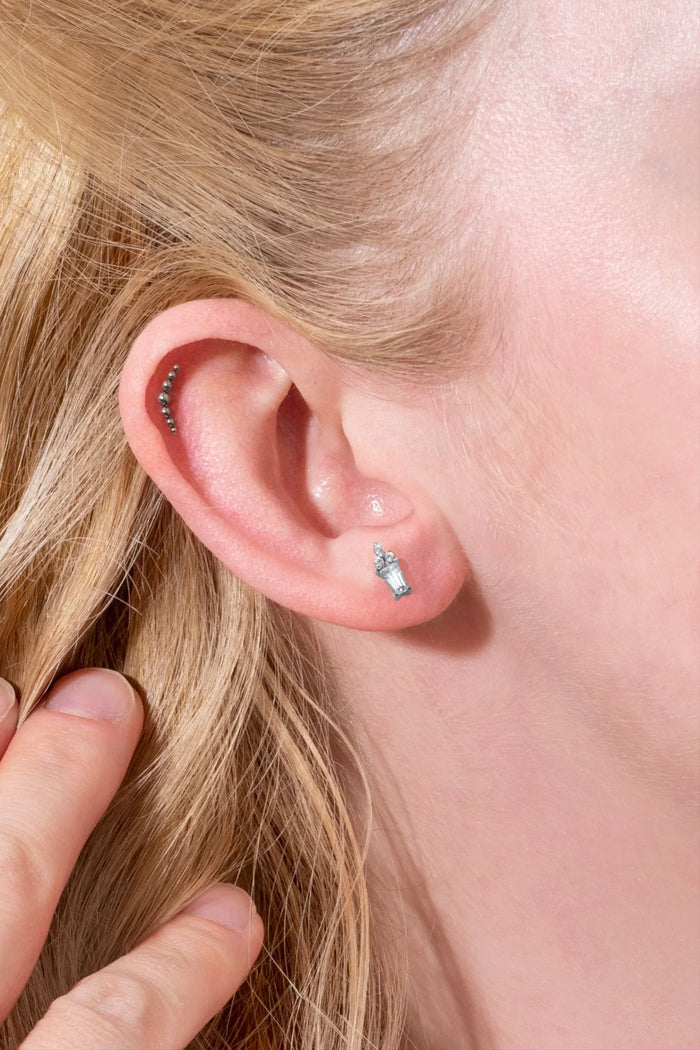 Close-up of a person's ear with earrings and blonde hair.