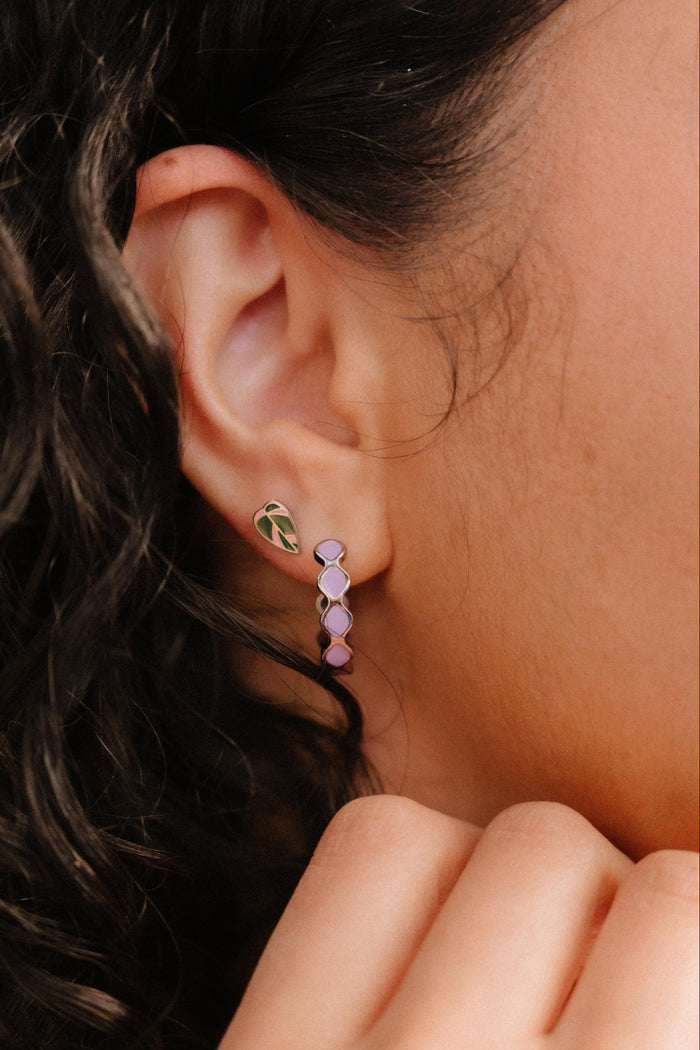 Close-up of an ear wearing a colorful earring with a blurred background