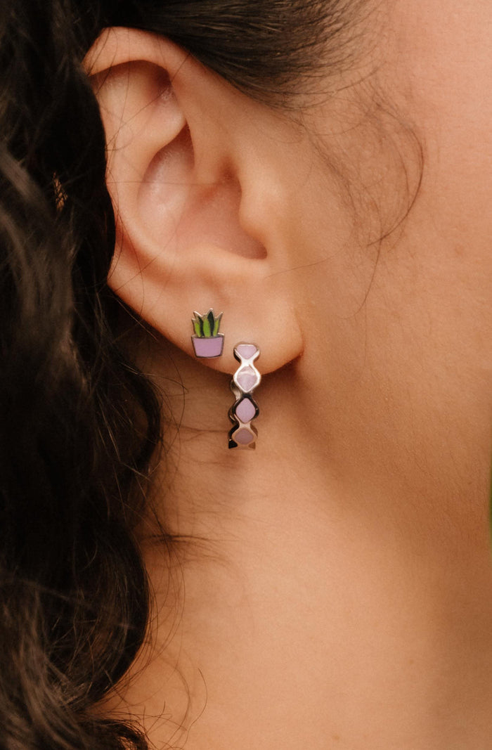 Close-up of a person wearing a purple hoop earring with a blurred background